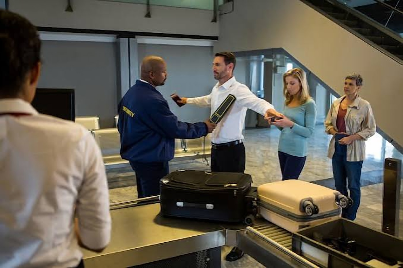 Security officer screening visitors with a hand scanner